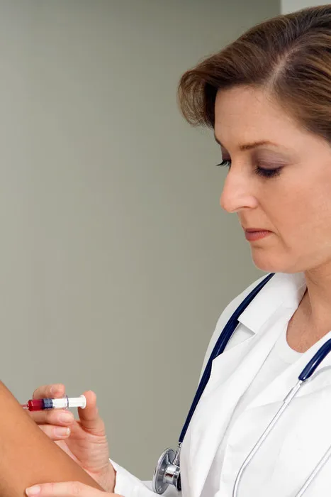 A female doctor examining a vial of medication.