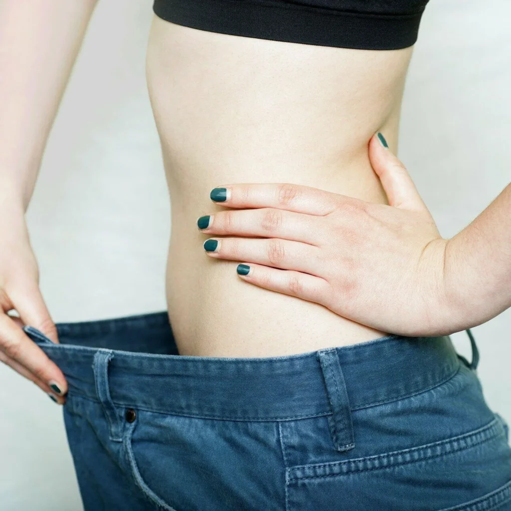 Person showing loose pants to highlight weight loss.