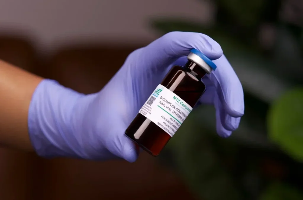 Gloved hand holding a vial labeled COVID-19 vaccine.